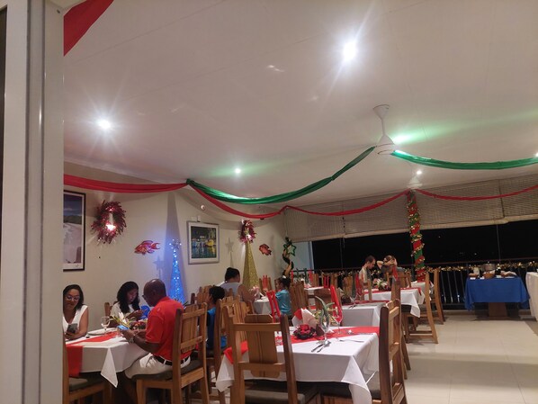 A restaurant with multiple tables, wooden chairs, and festive decorations.