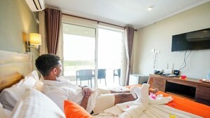 Une chambre d’hôtel avec un lit, une télévision, un bureau et une vue sur l’extérieur, visible à travers une porte vitrée.