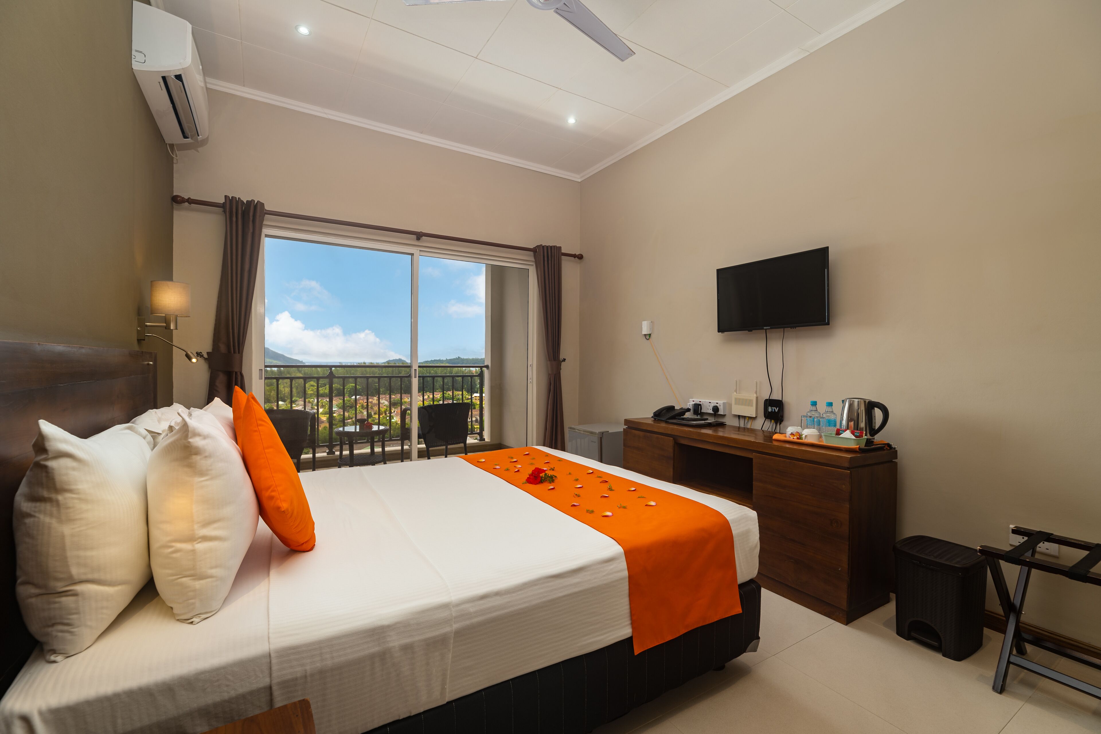 A hotel room with a bed, a desk, a TV, and a window with a view.
