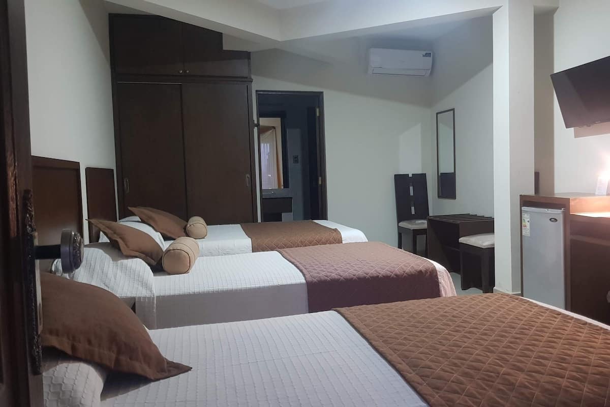 Habitación de hotel con dos camas, un escritorio, una silla, un televisor y un refrigerador.