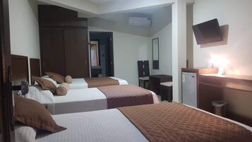 A hotel room with two beds, a desk, a chair, a television, and a refrigerator.