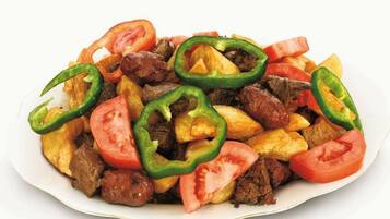 Un plato de comida con rodajas de tomate y pimiento verde.