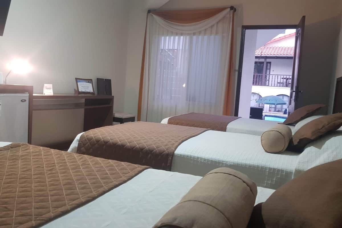 Habitación de hotel con dos camas, un escritorio con ordenador y una ventana con cortinas.