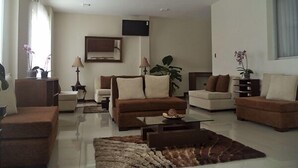 Una sala de estar moderna con sofás, una mesa de centro y un televisor montado en la pared.