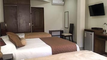 Habitación de hotel con dos camas, un escritorio, una silla, un televisor y un equipo de aire acondicionado.