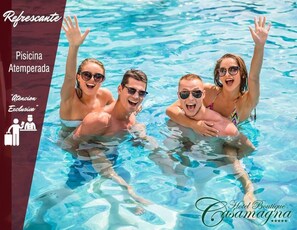 Uma piscina com água azul cristalina, rodeada por uma borda listrada em vermelho e branco.