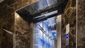 An elevator with a glass door, marble walls, and a digital display. - Fi Homes - Adults Only (Izmir)