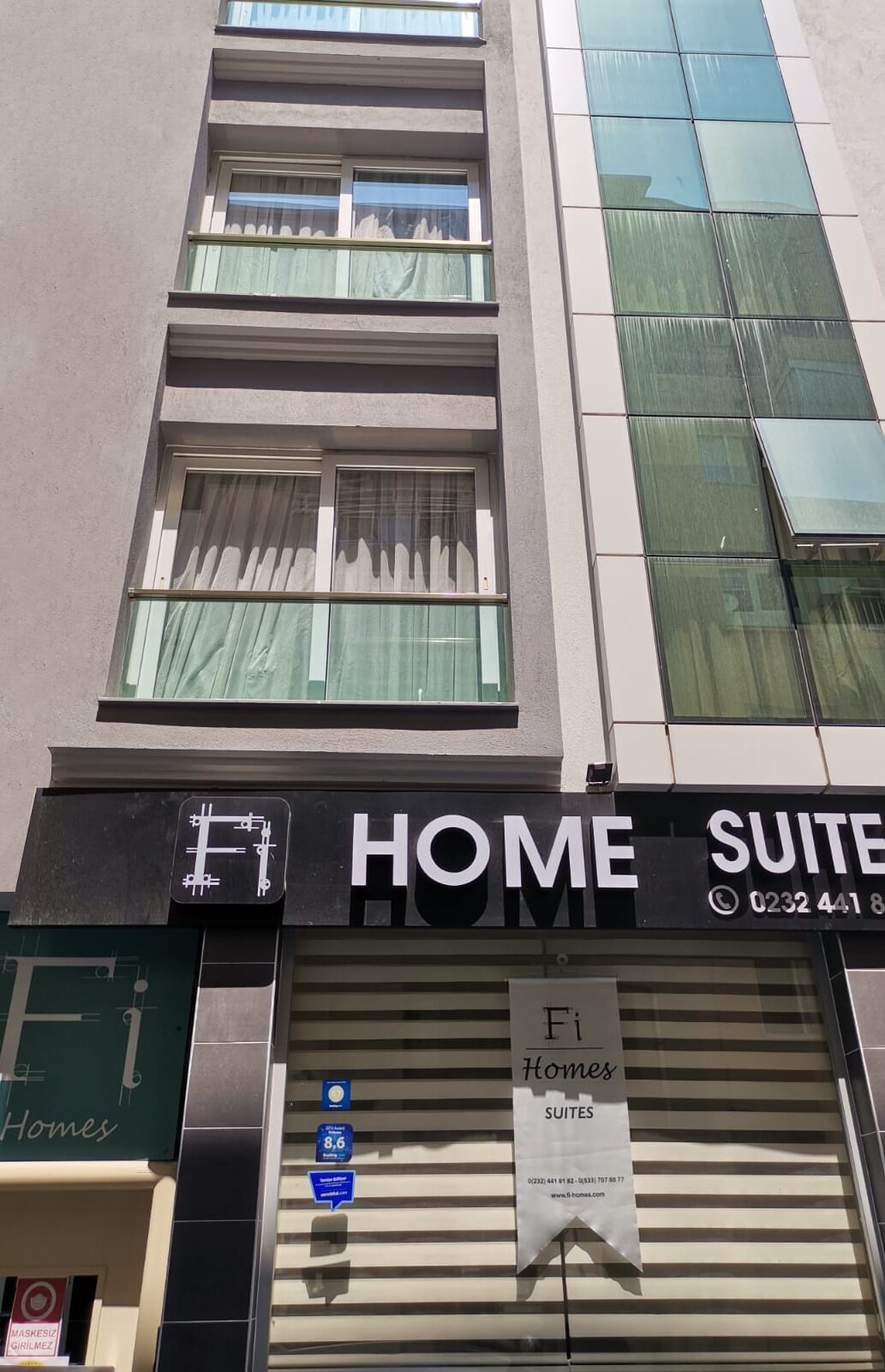 Un immeuble avec une enseigne indiquant « HOME SUITES » et un numéro de téléphone à contacter.