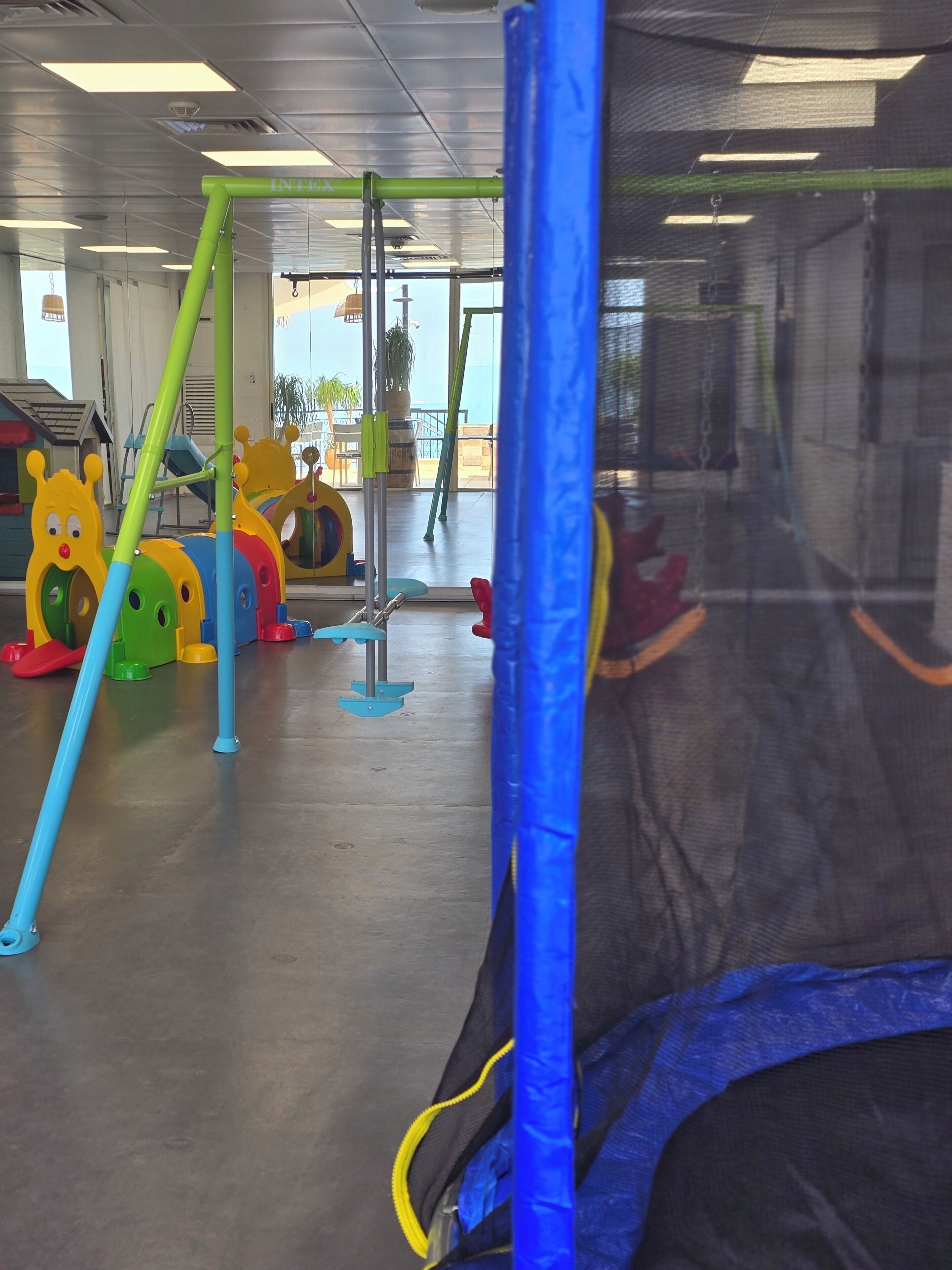 A children's play area with various colorful play structures, including a slide and climbing frames.