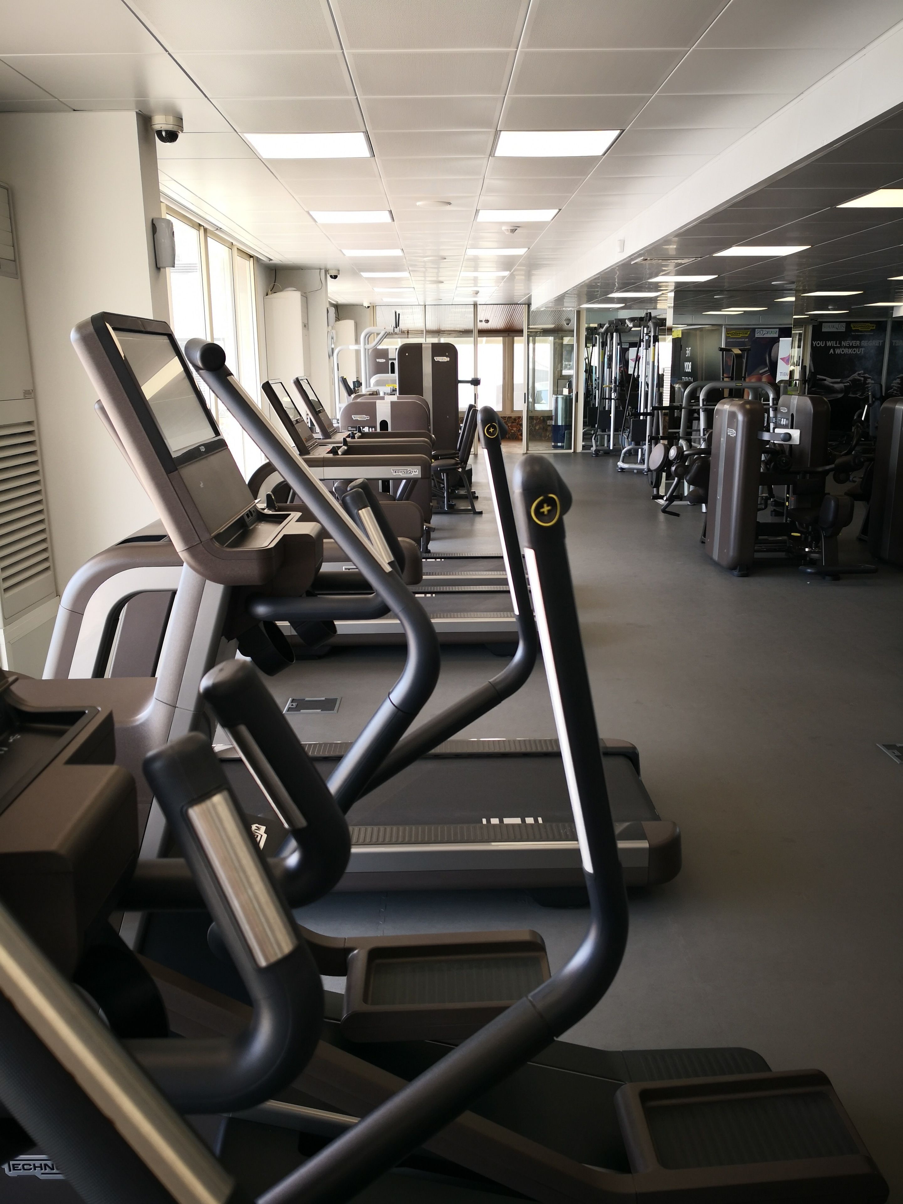 Een fitnessruimte met loopbanden, krachttoestellen en trainingsapparatuur.