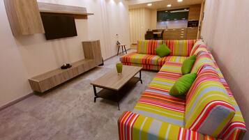 A modern living room with a sofa set, a coffee table, and a TV mounted on the wall.