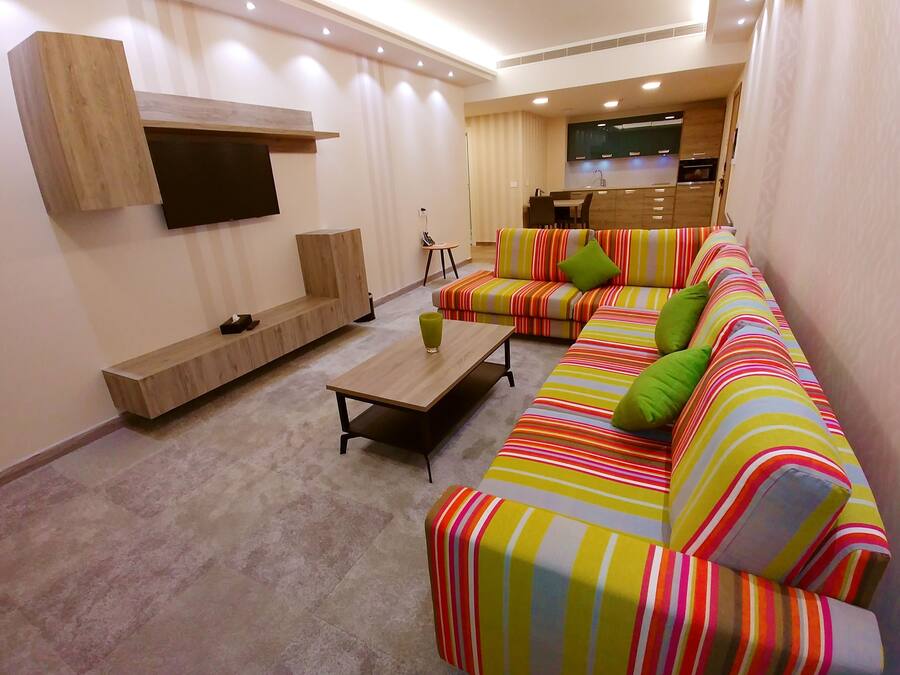 A modern living room with a sofa set, a coffee table, and a TV mounted on the wall.