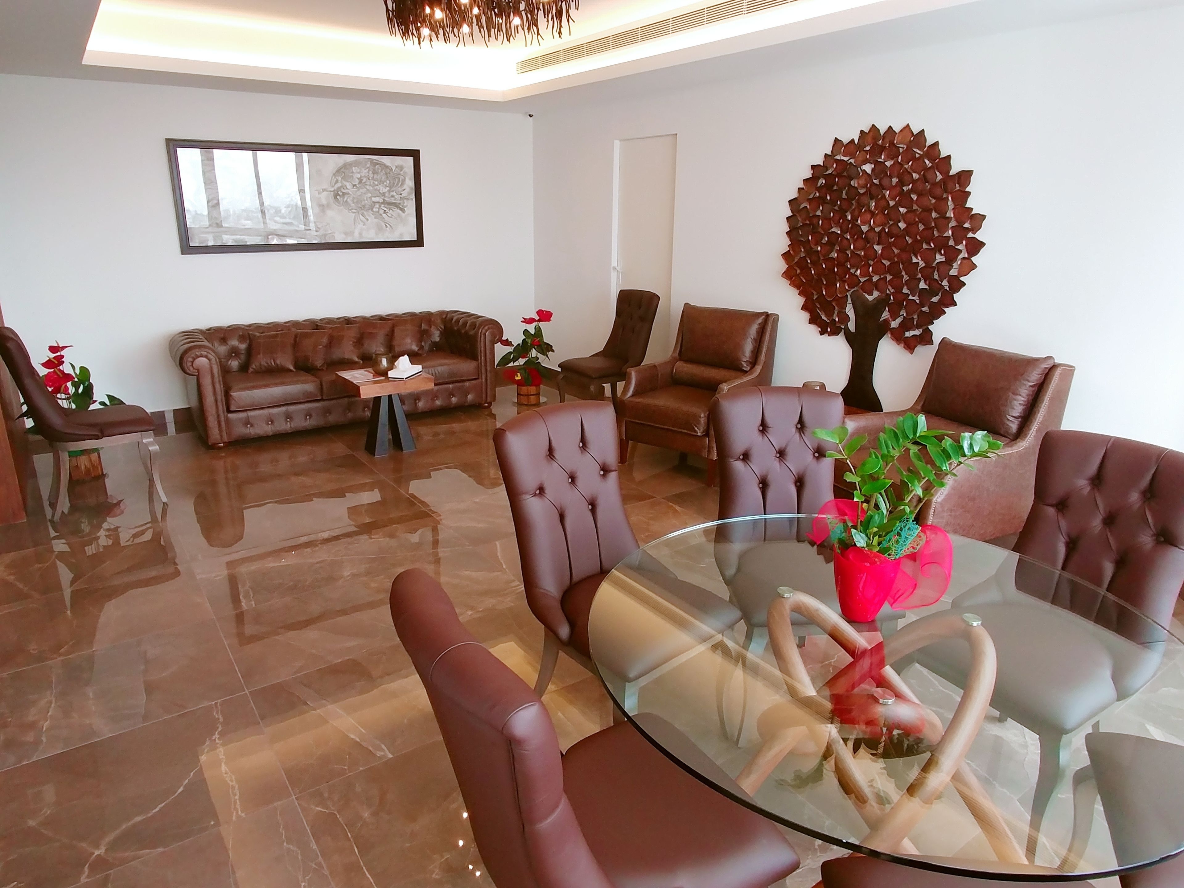 Ein modernes Wohnzimmer mit einem Glastisch, Ledersofas und Sesseln.