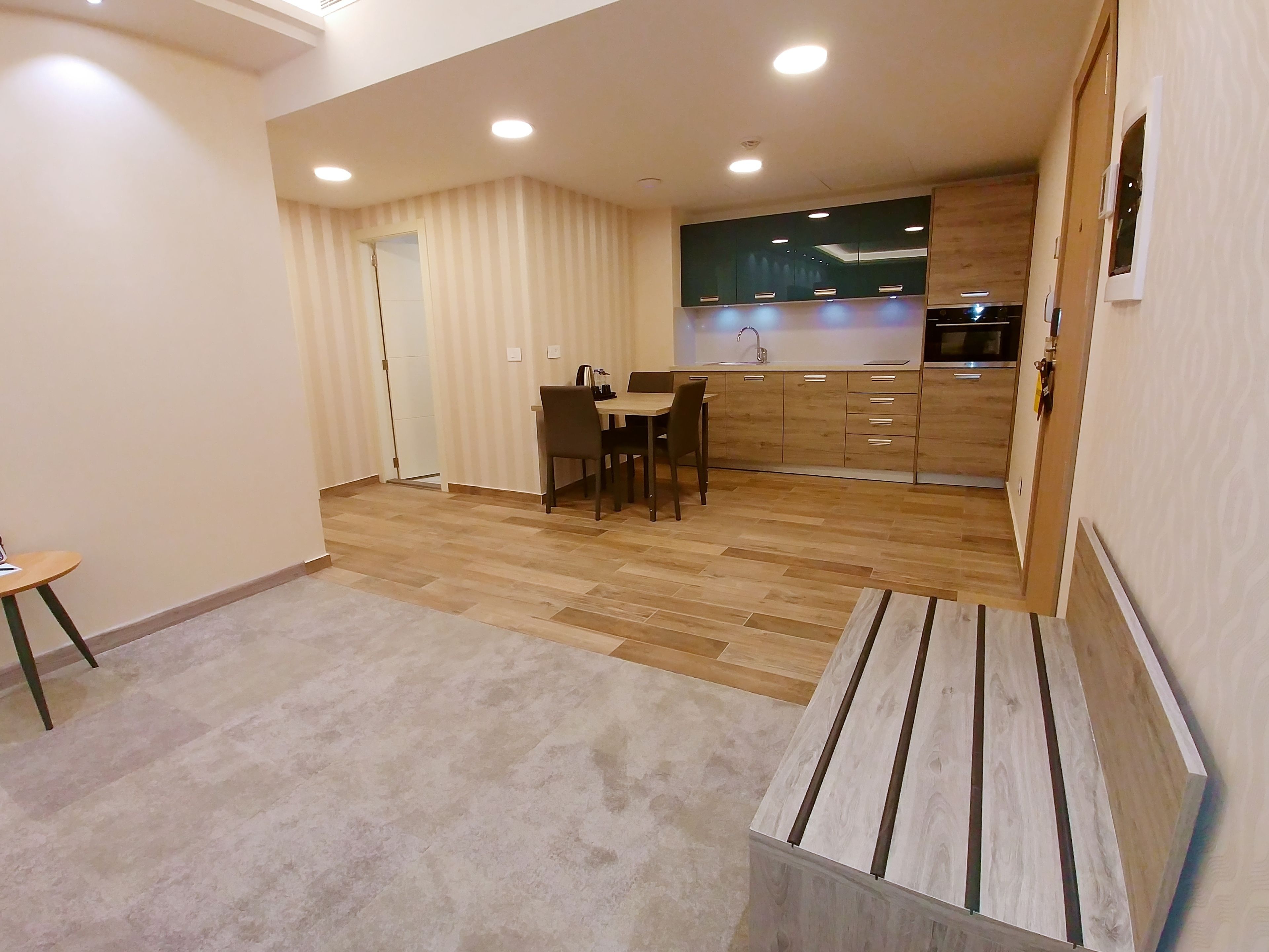 Una cocina moderna con armarios de madera, una zona de comedor con mesa y sillas, y piso alfombrado.