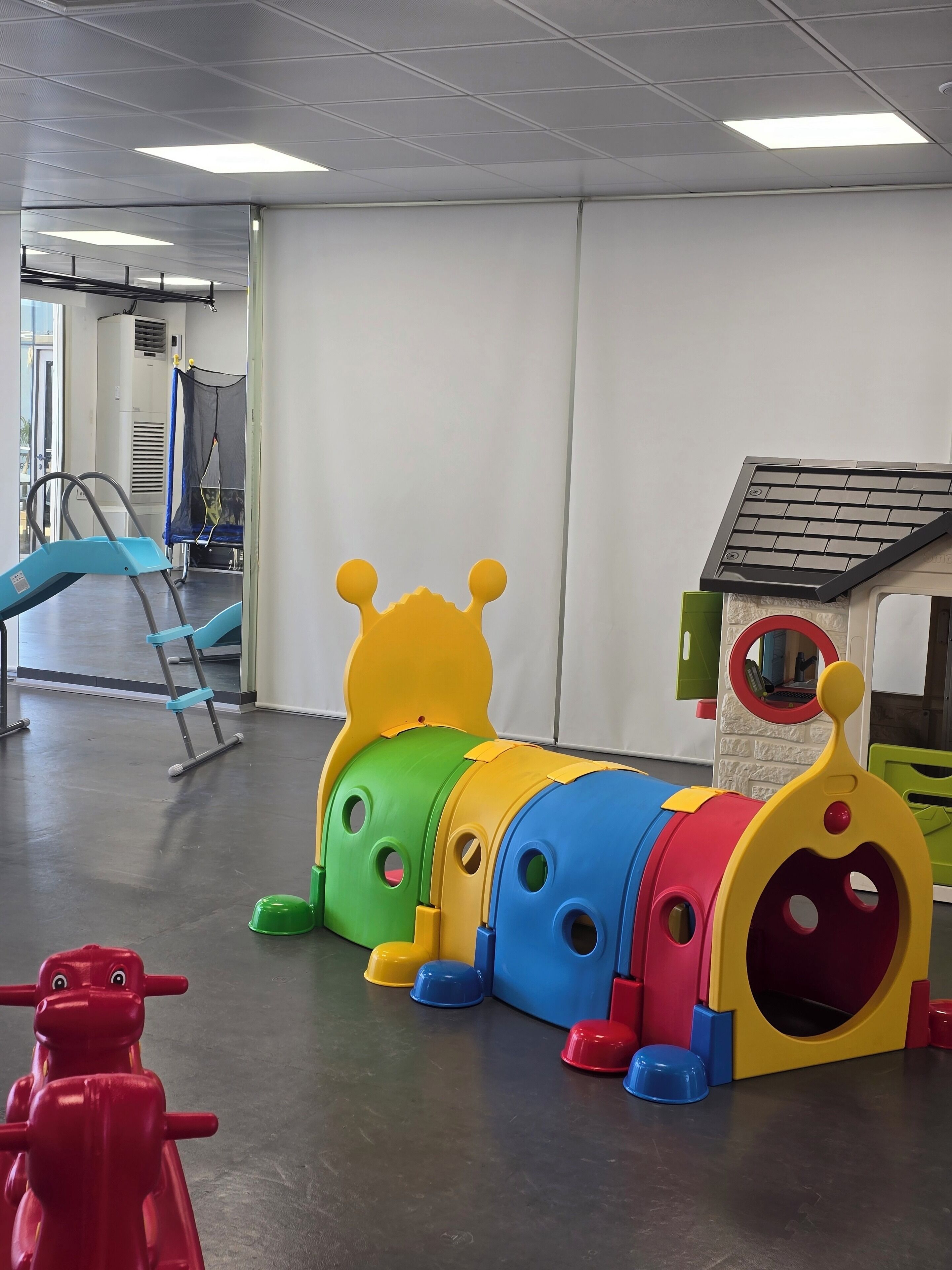 Zona de juegos infantiles con un colorido tren de juguete y una pequeña casita.