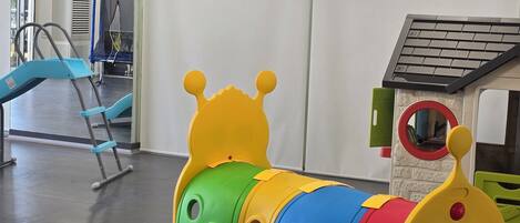 Zona de juegos infantiles con un colorido tren de juguete y una pequeña casita.