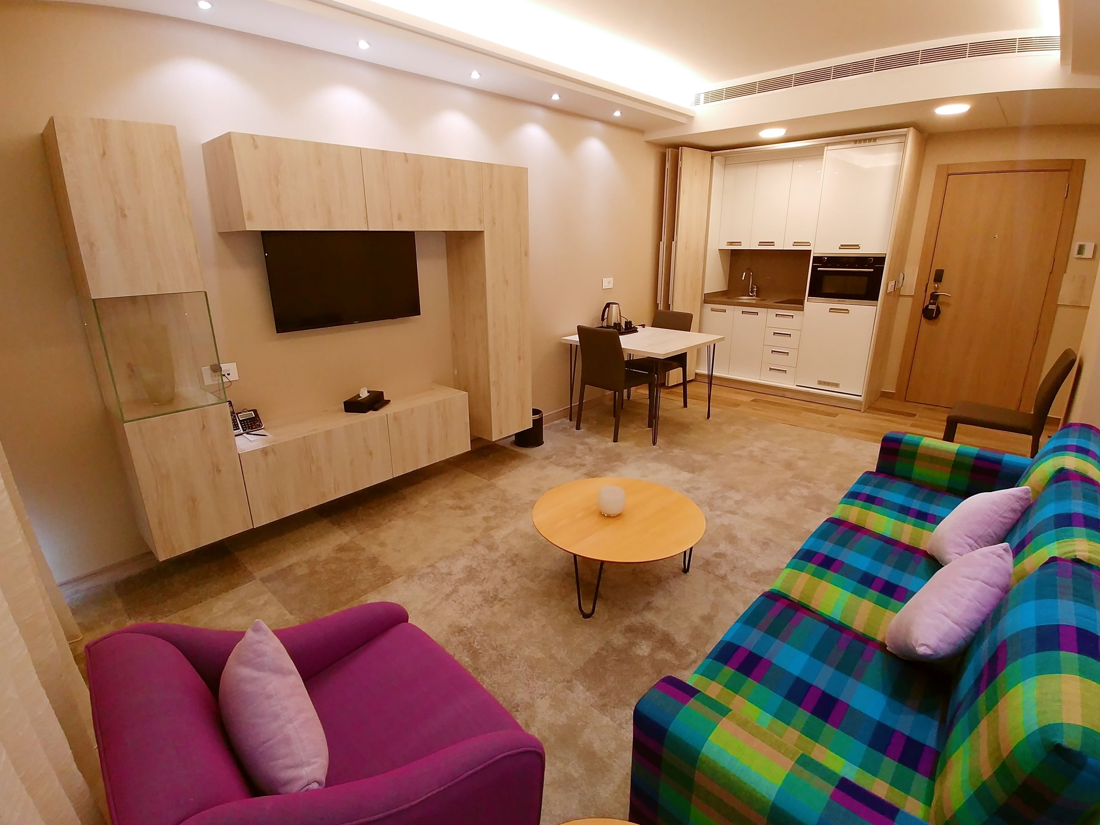 A modern living room with a sofa, a coffee table, and a TV mounted on the wall.