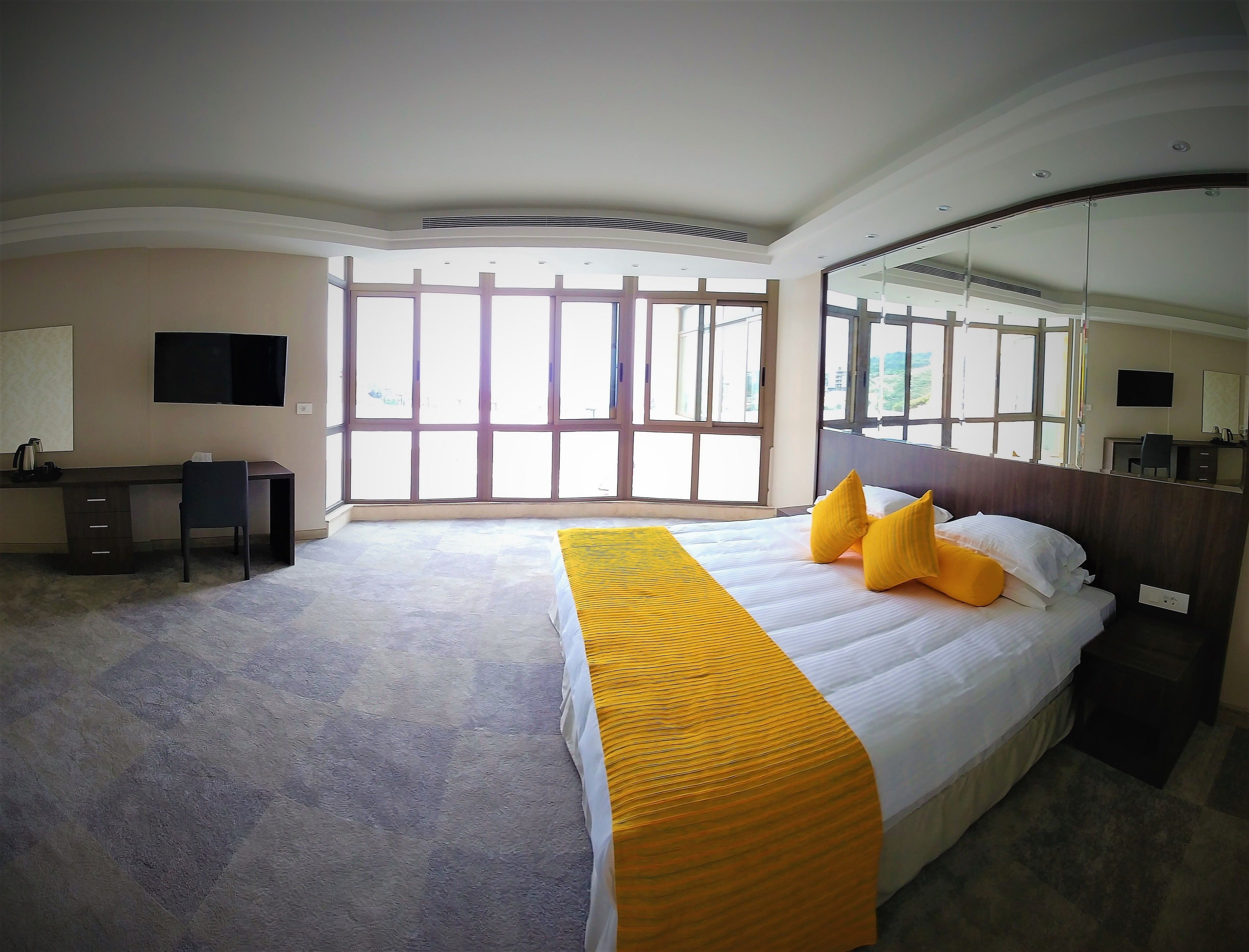 A hotel room with a large bed, a desk, and a TV.