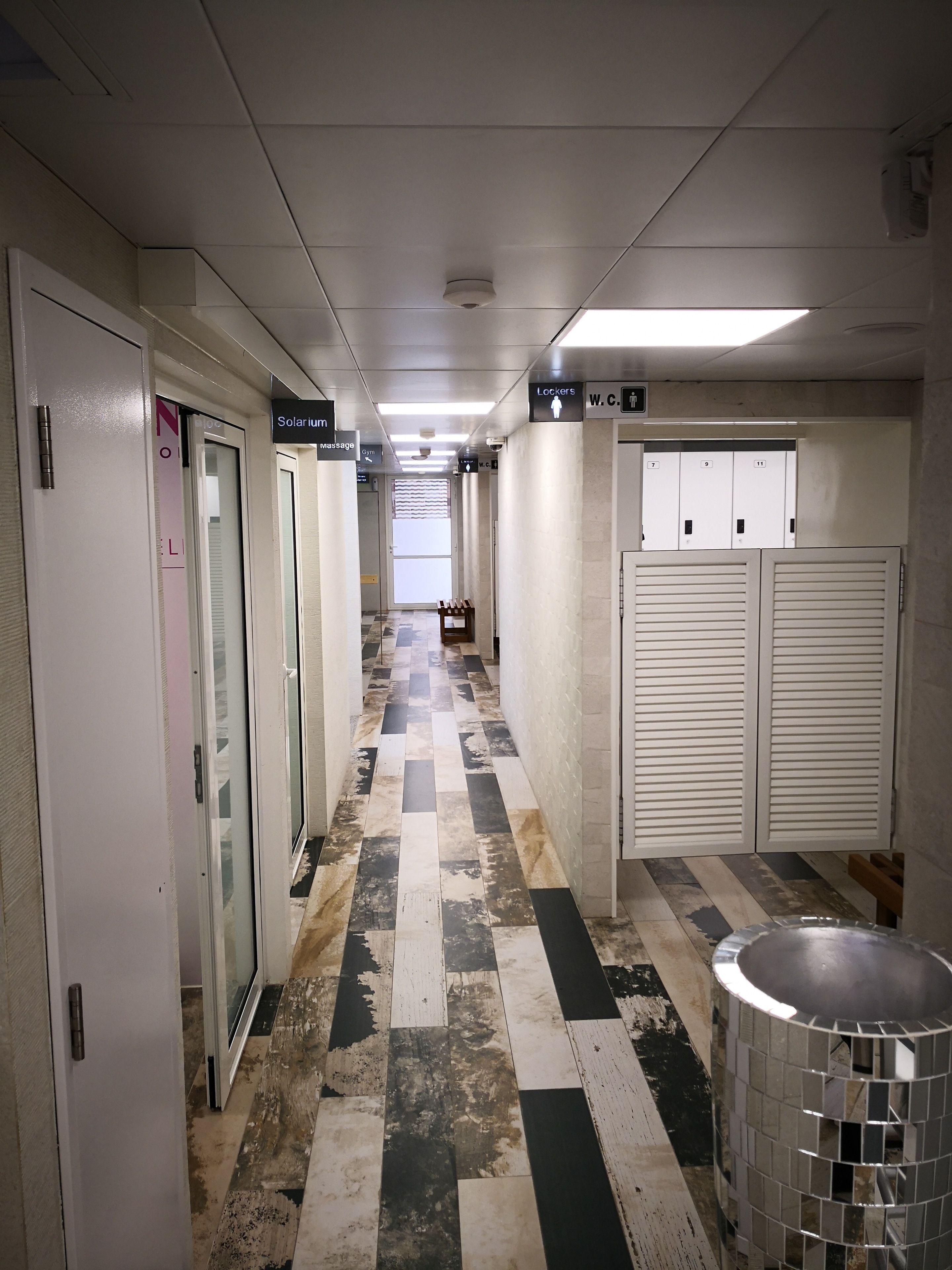 A hotel corridor with lockers, a massage room, and a W.C. sign.