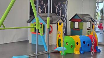 Uma área de recreação infantil com baloiço, estruturas de jogos coloridas e escorrega.