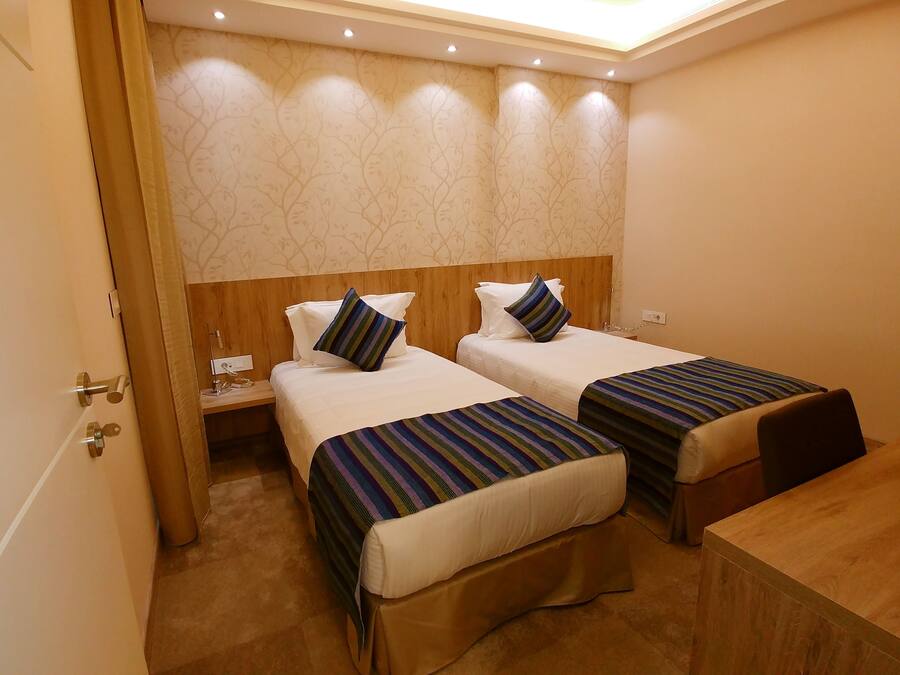 A hotel room with two beds, wooden headboards, and a nightstand with a lamp.