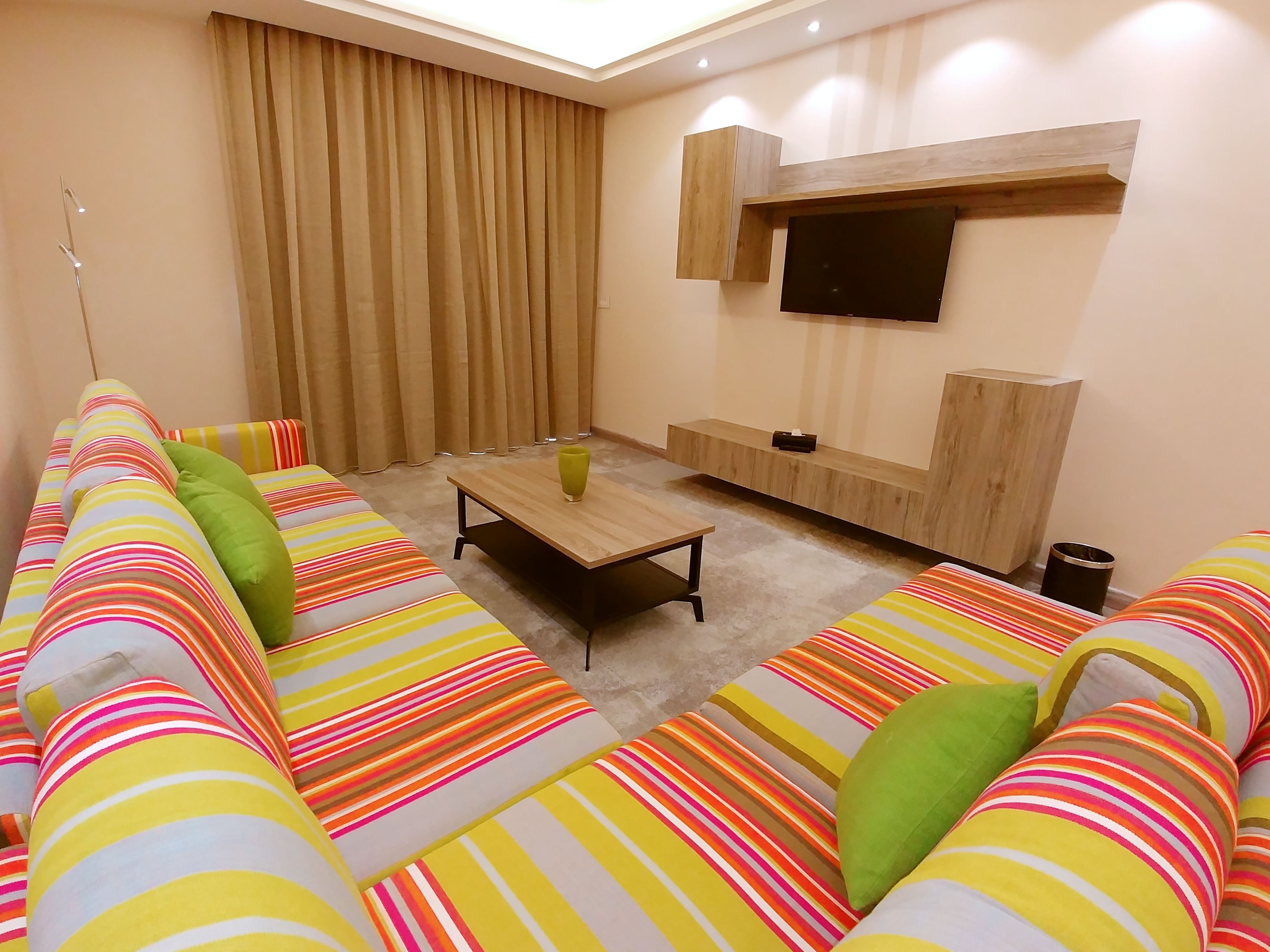 Una sala de estar moderna con un conjunto de sofá, una mesa de centro y un televisor de pantalla plana montado en la pared.