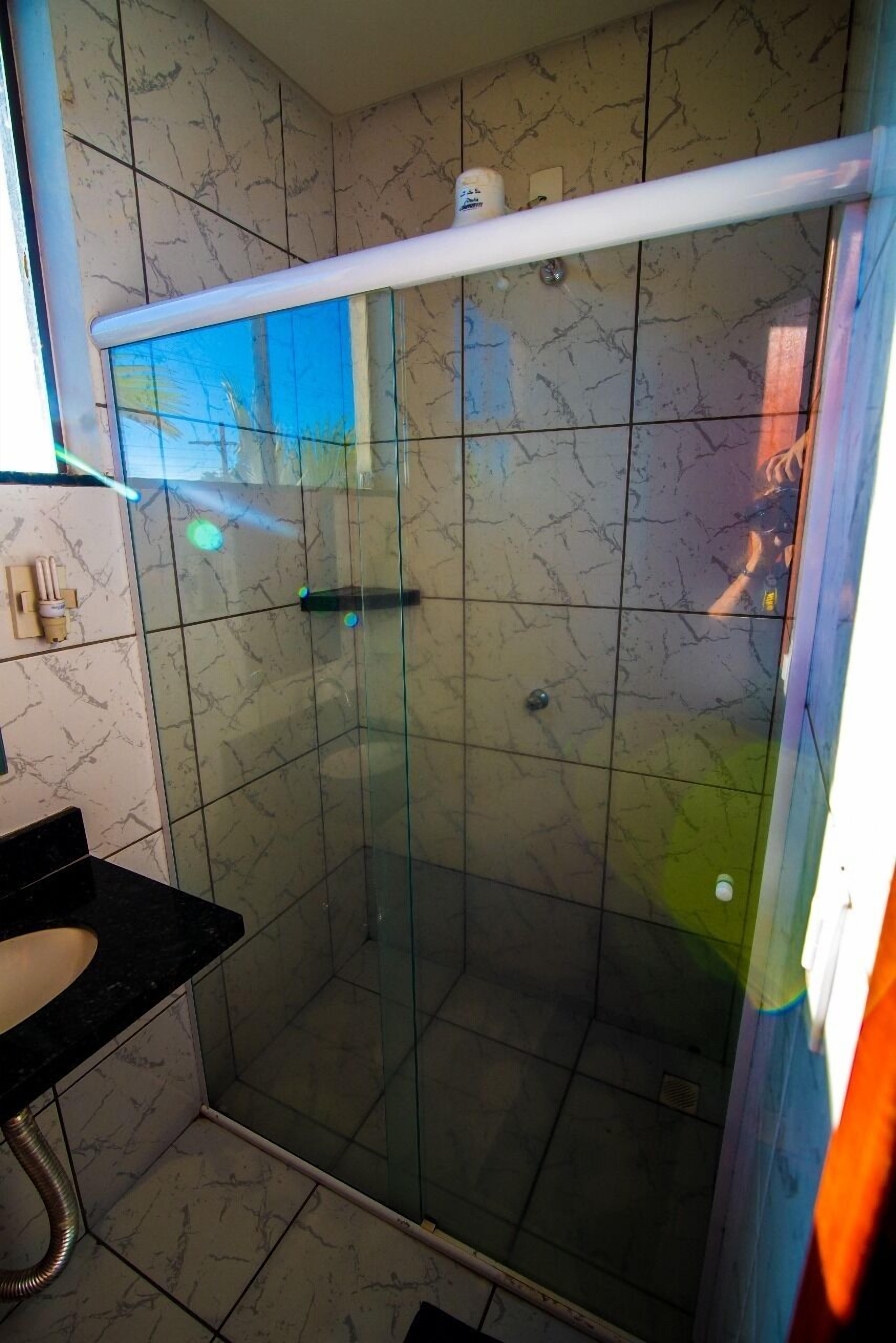Una ducha con cerramiento de vidrio, techo blanco y paredes con azulejos.