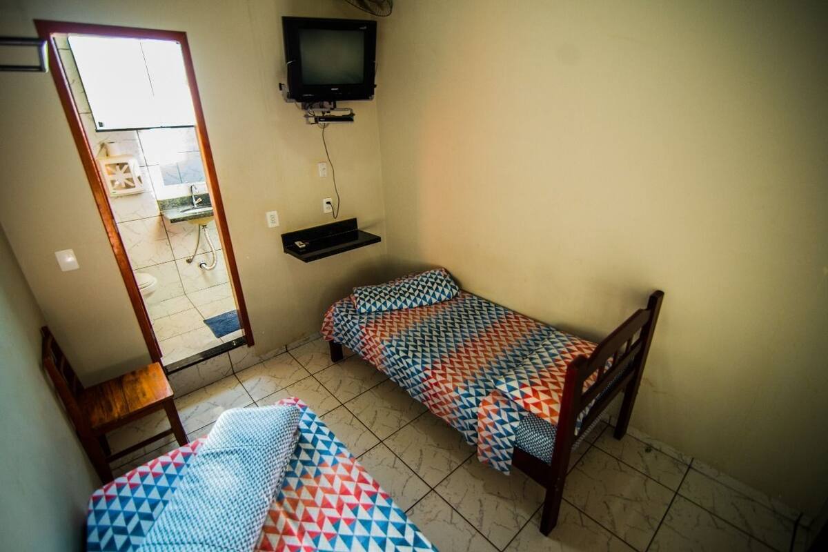 A small room with two beds, a TV, and a mirror.
