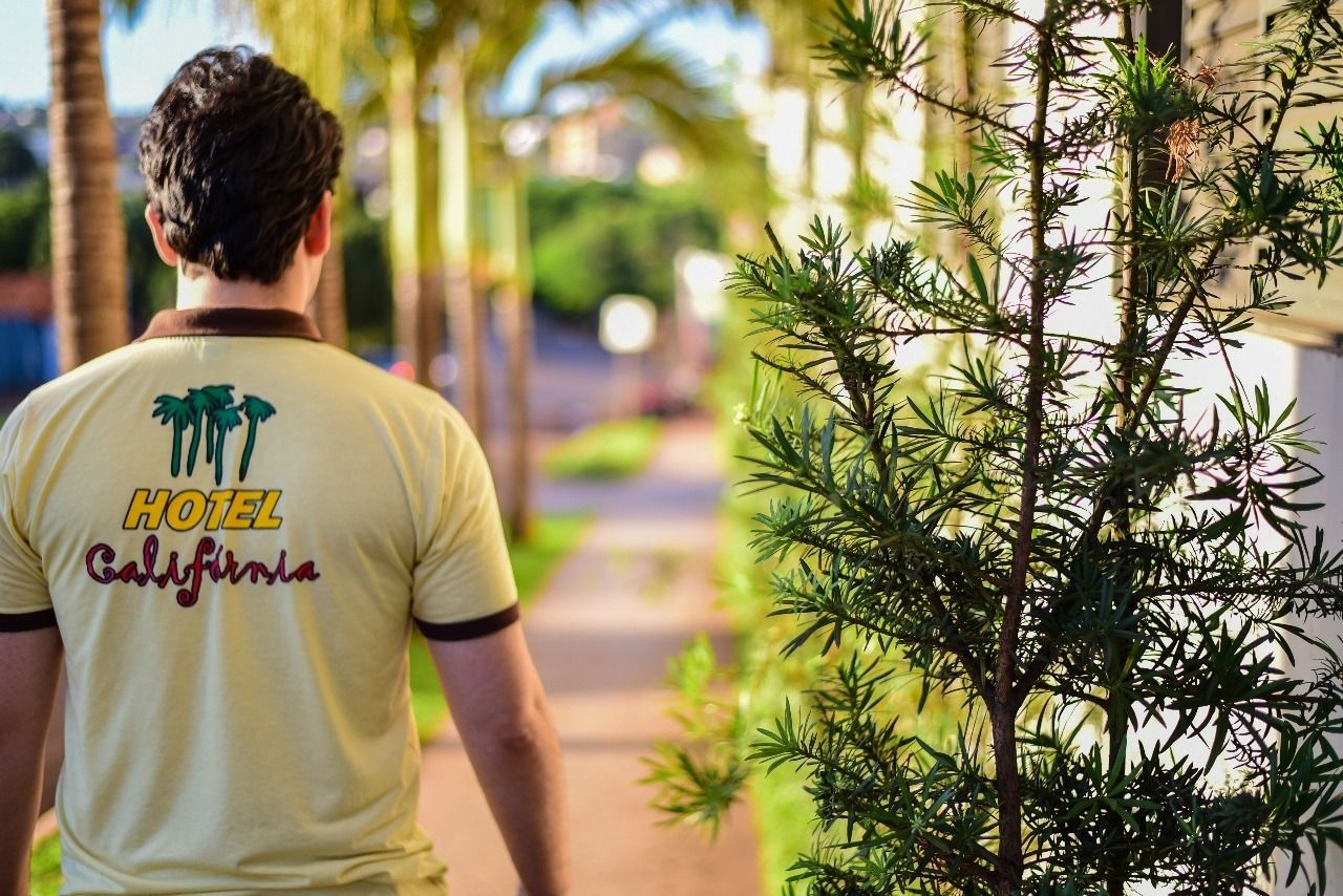 A person wearing a hotel staff uniform with palm trees and the text "HOTEL California" on the back.