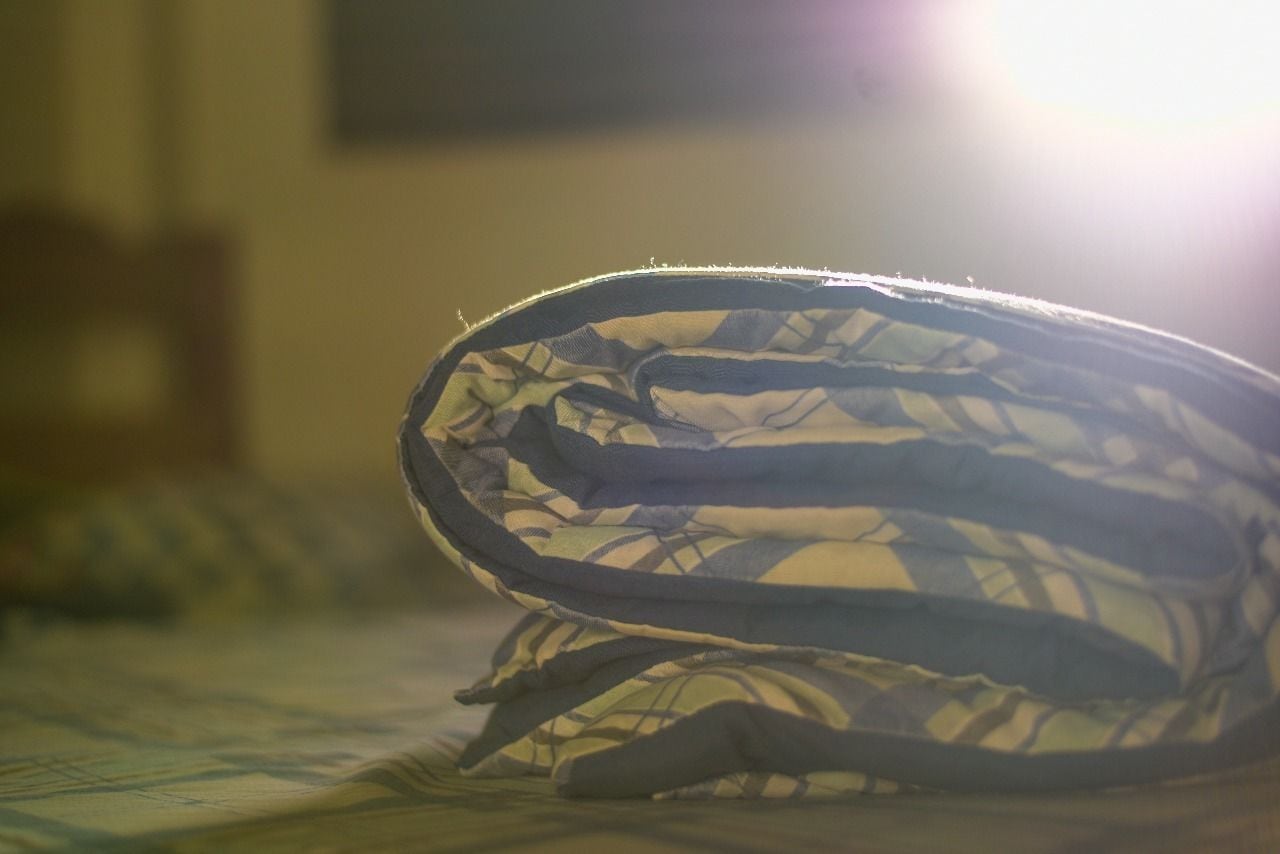 Mochila dobrada sobre uma cama.
