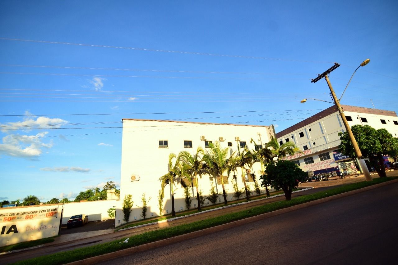 Un edificio de fachada blanca, palmeras al frente y un cielo azul despejado.