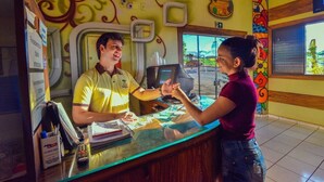 A counter with a glass top, a computer monitor, and a menu board. - Hotel Califórnia (Jatai)