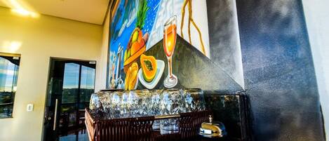 Zona de bar con un mural de frutas tropicales y una copa de champán.