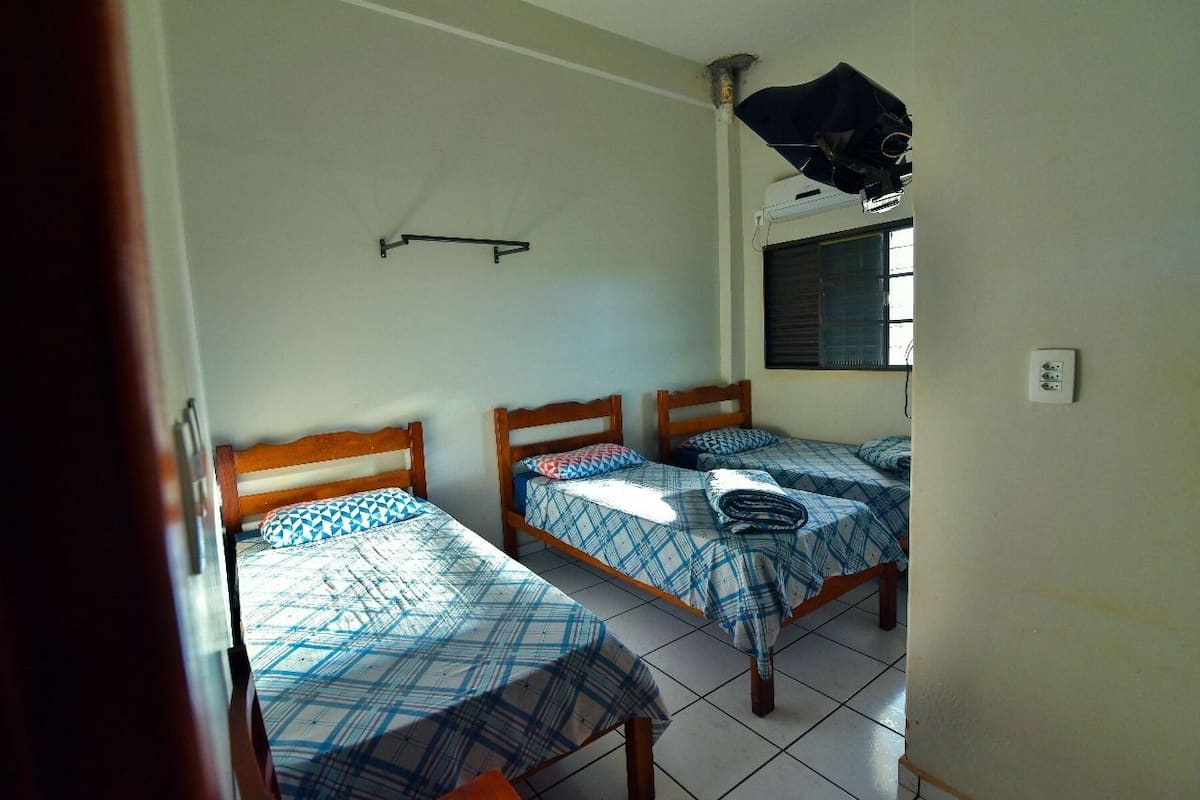 A room with two single beds, a window, and a ceiling fan.