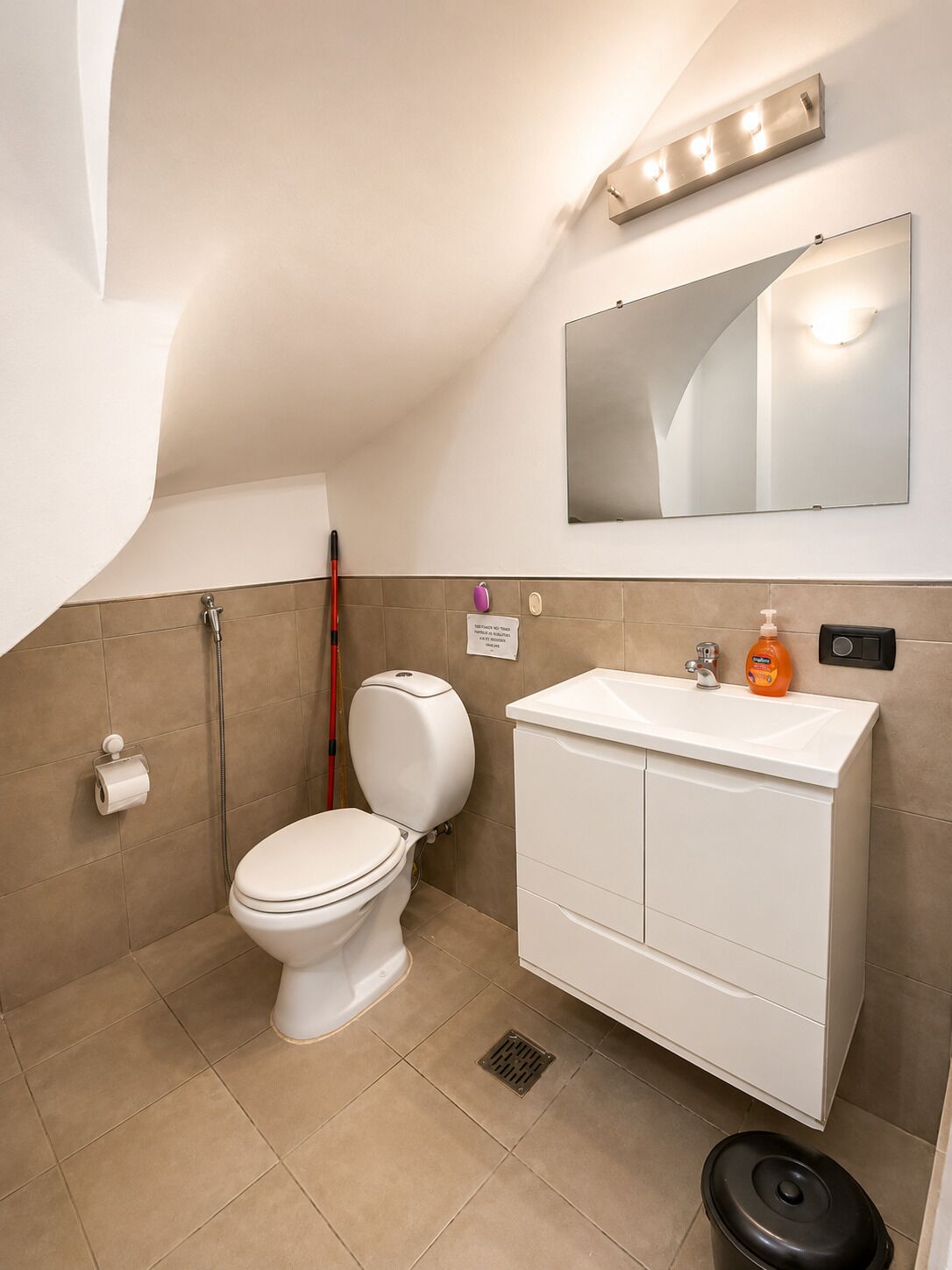 Un baño con inodoro, lavamanos, espejo y ducha.