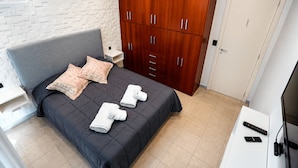 A hotel room with a bed, wooden wardrobe, bedside table, and a TV. - Casa Colinas (Mar del Plata)