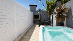 Un jardin avec un jacuzzi, un barbecue et du mobilier d’extérieur.
