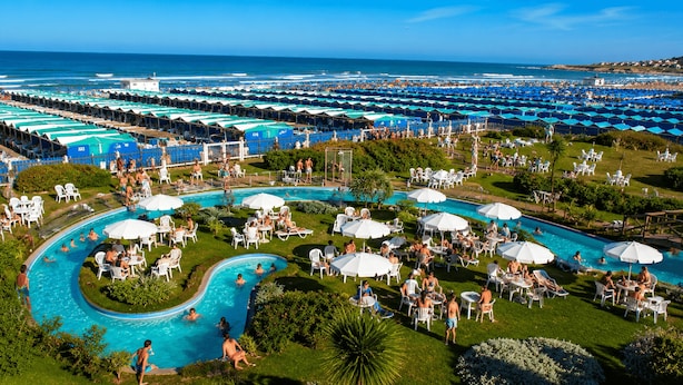 A resort with multiple swimming pools, sun loungers, and umbrellas. - Casa Colinas (Mar del Plata)