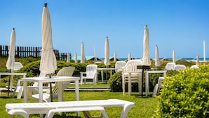 Outdoor seating with umbrellas, a wooden fence, and a view of the ocean. - Casa Colinas (Mar del Plata)