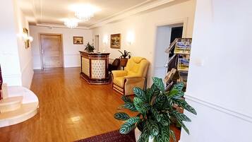 A spacious living area with a wooden staircase, a yellow armchair, a wooden cabinet, and a potted plant.