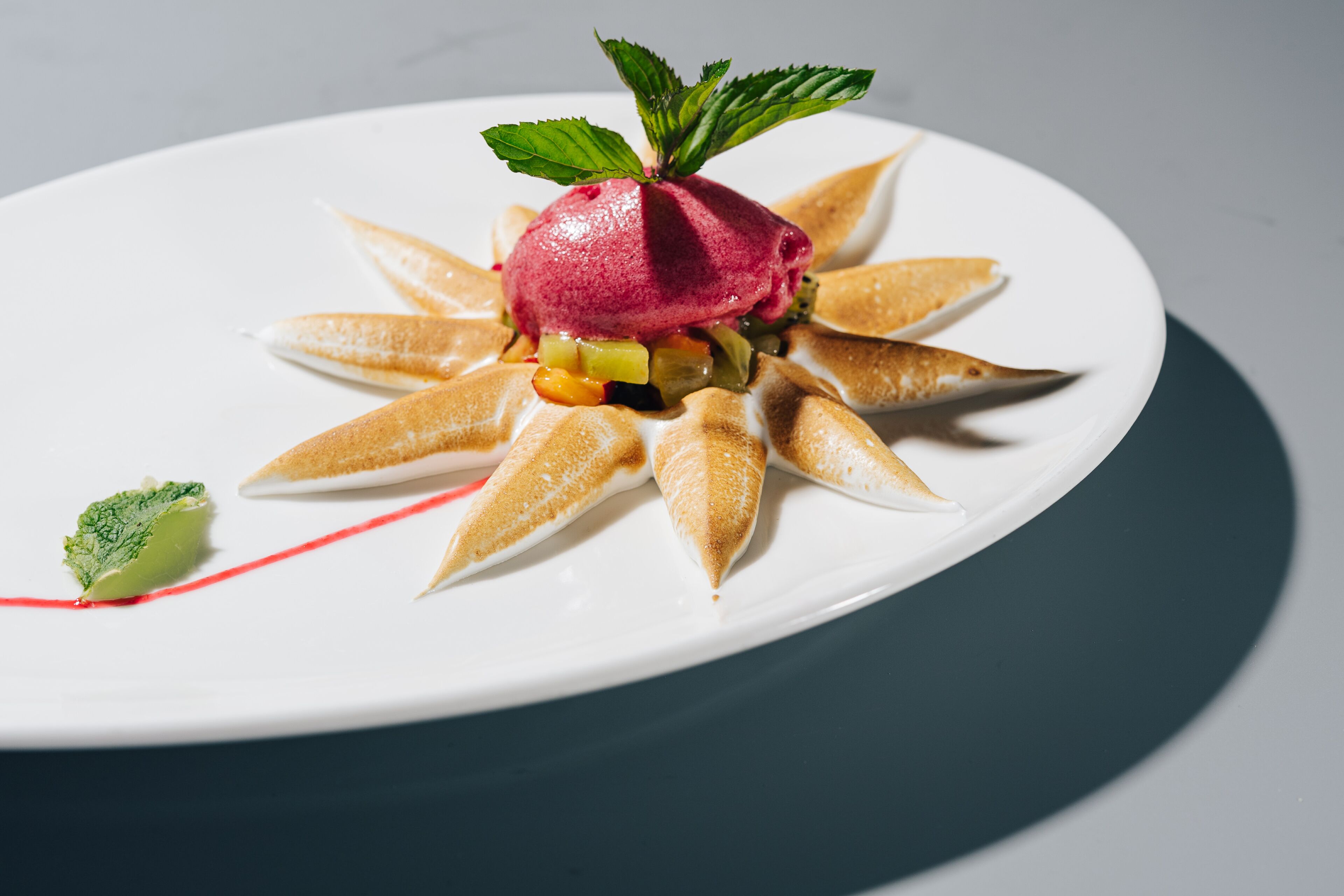 A dessert on a white plate with a mint leaf garnish.