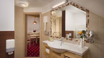 A modern bathroom with a large mirror, a sink, and a shower. There is a wooden vanity and a red carpeted area.