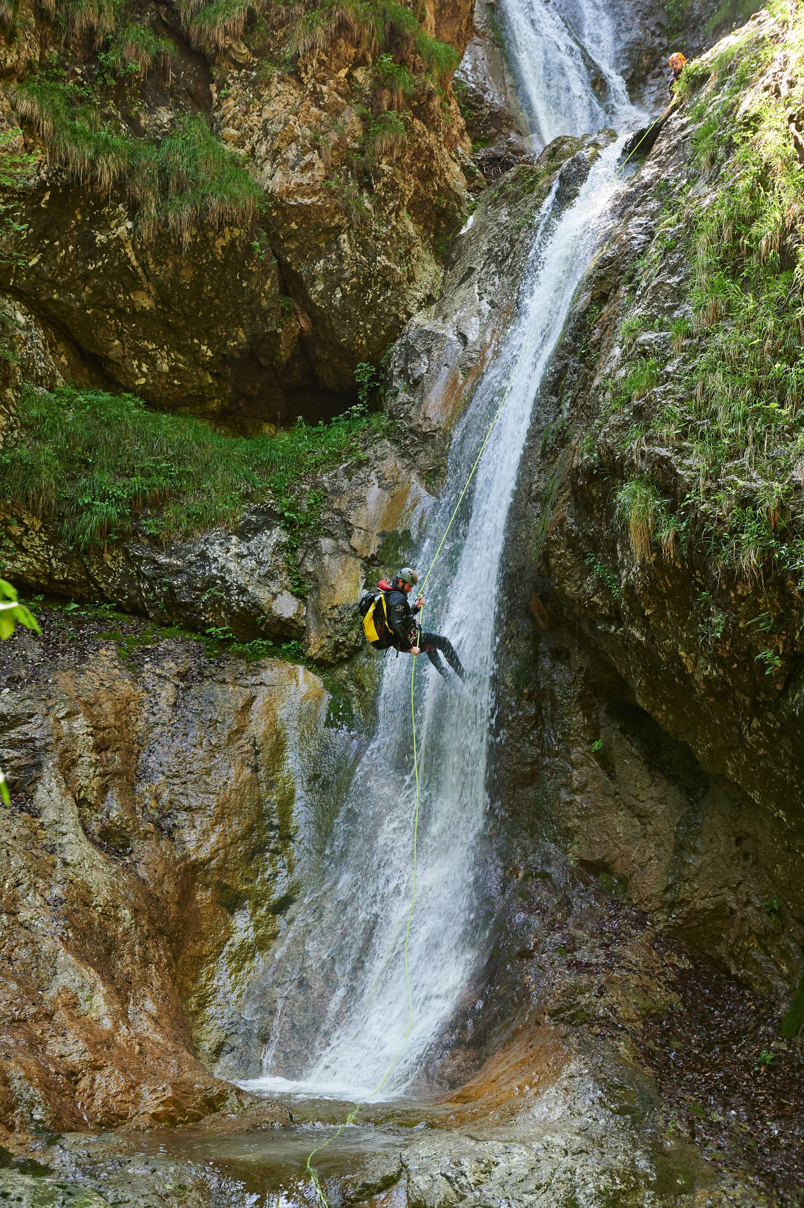 A person rappelling down a waterfall.