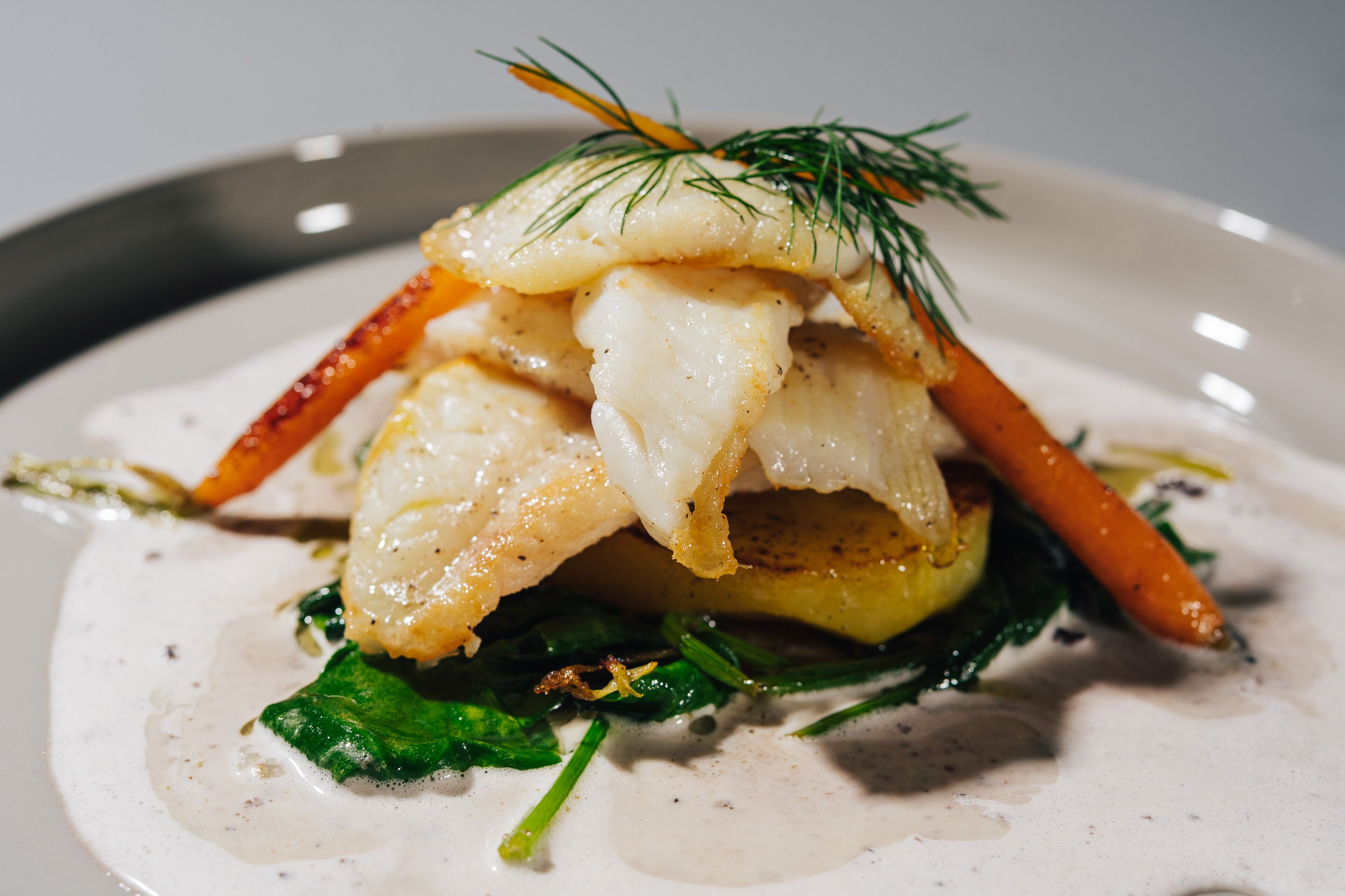 A dish with fish, vegetables, and a garnish.
