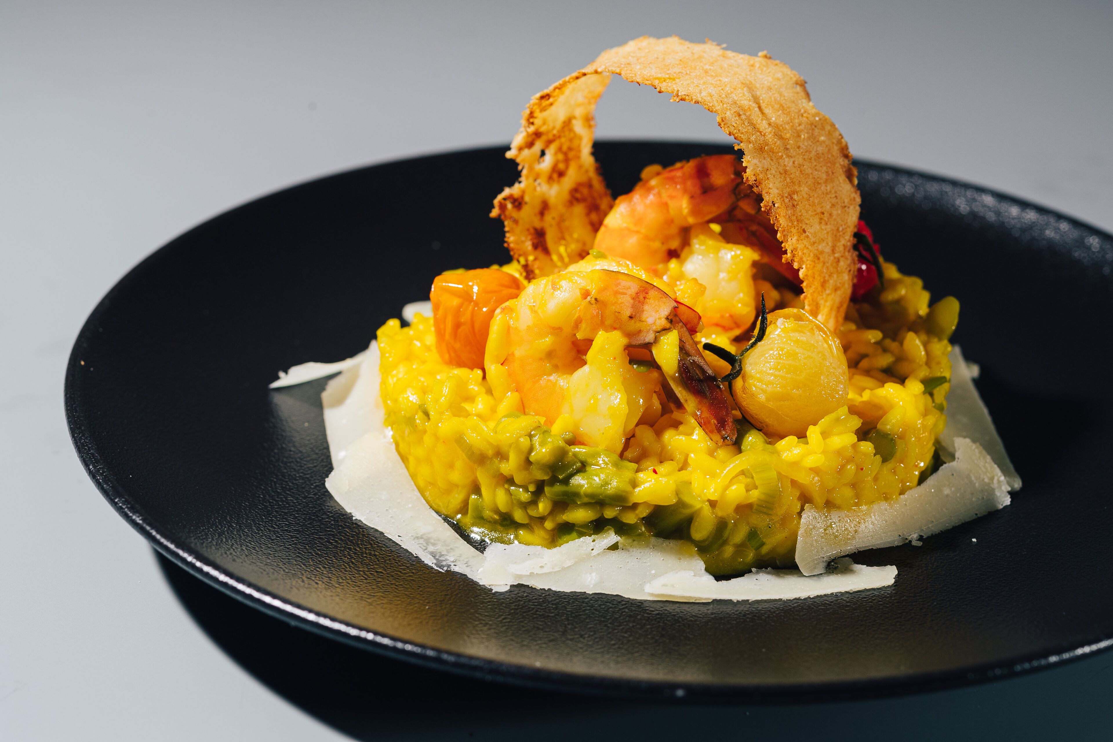 A dish with shrimp, rice, and vegetables on a black plate.