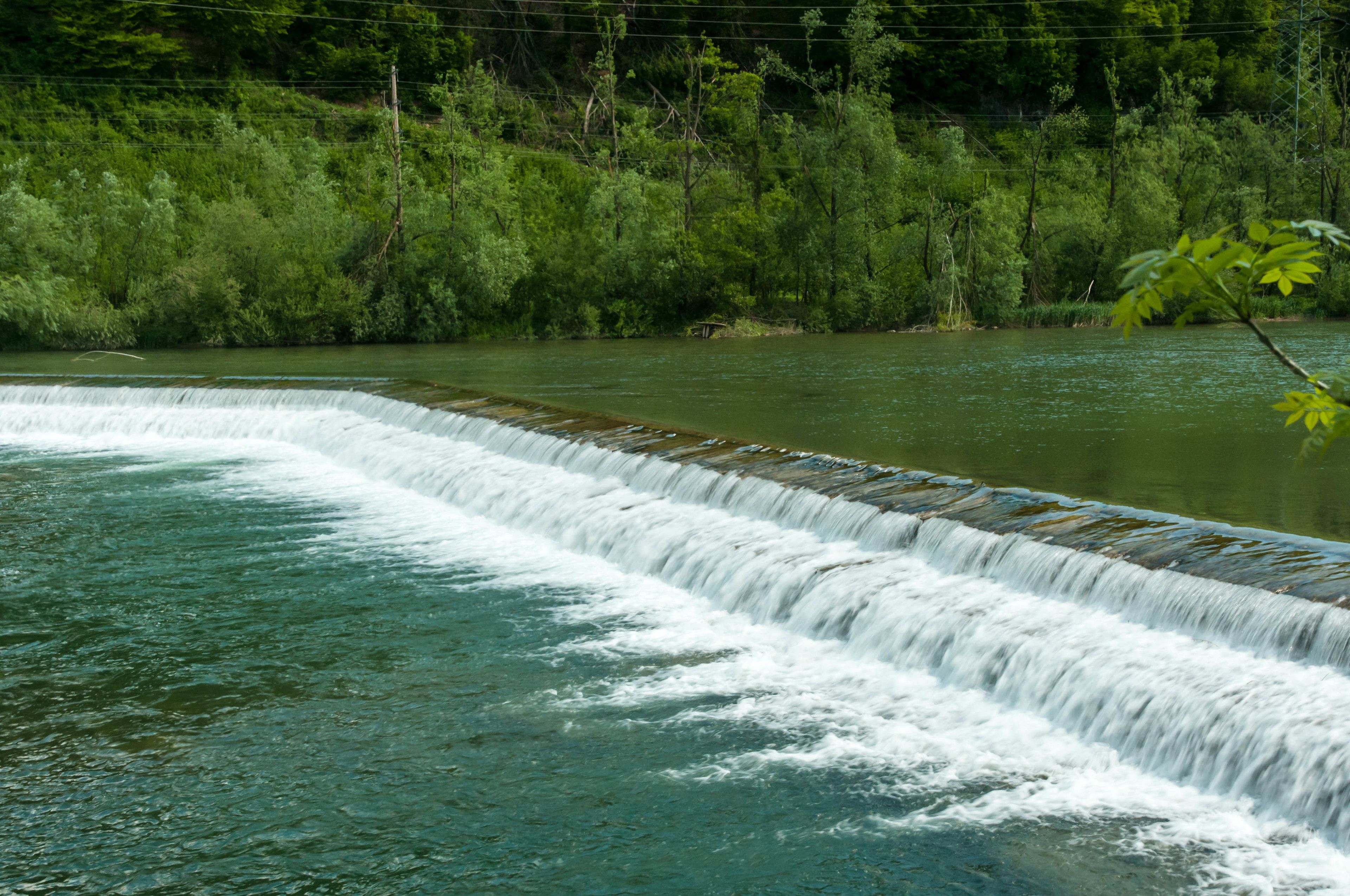 A river with a concrete weir creating a small waterfall.