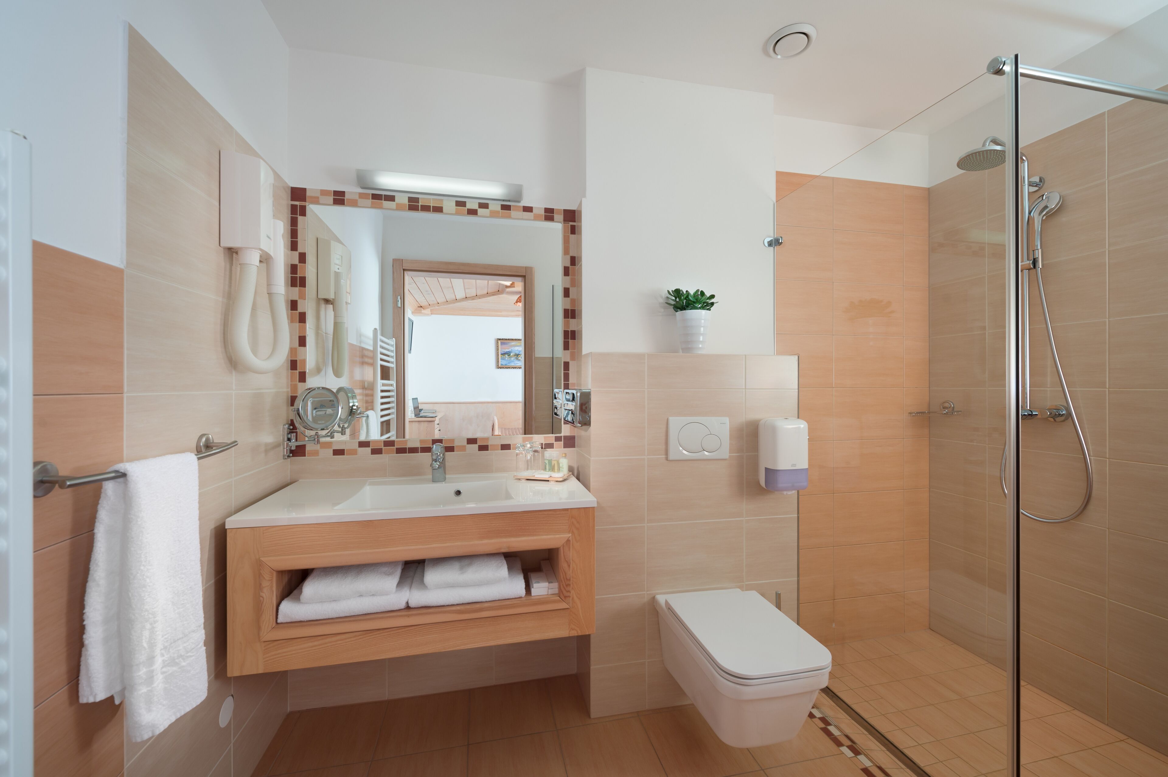 Un baño moderno con lavamanos, espejo, toallero, inodoro y ducha.