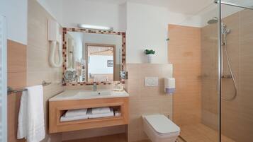 Un baño moderno con lavamanos, espejo, toallero, inodoro y ducha.