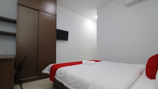 A bedroom with a bed, a wardrobe, a TV, and a chair. - RedDoorz Plus Near Kepri Mall (Batam)