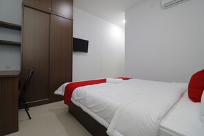 A bedroom with a bed, a wardrobe, a TV, and a chair. - RedDoorz Plus Near Kepri Mall (Batam)